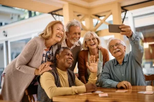 Grupo de pessoas longevas sorriem de forma descontraída fazendo uma selfie